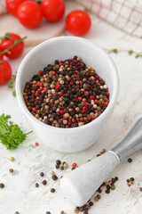 Mortar and pestle with peppercorns on light background