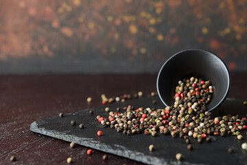 Bowl with peppercorns on dark background