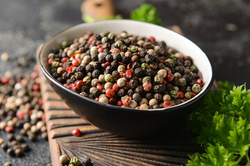 Bowl with peppercorns on dark background