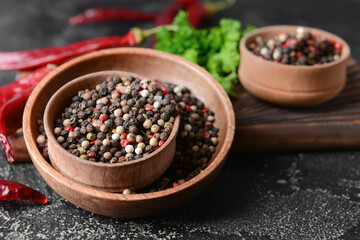 Bowls with peppercorns on dark background