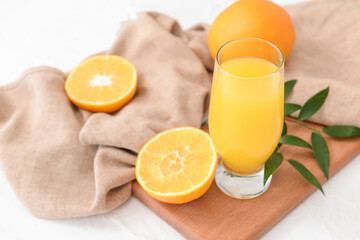 Glass with orange juice on light background