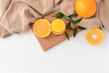 Glass with orange juice on light background