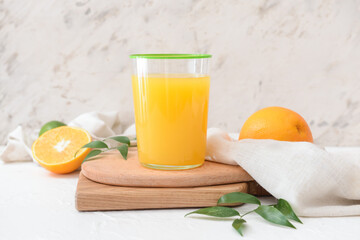 Glass with orange juice on light background