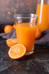 Glass with tangerine juice on dark background