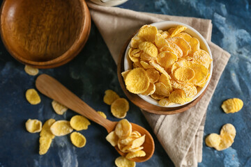 Bowl and spoon with tasty cornflakes on color background