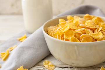 Bowl with tasty cornflakes on light wooden background