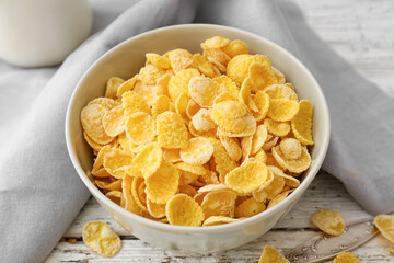 Bowl with tasty cornflakes on light wooden background