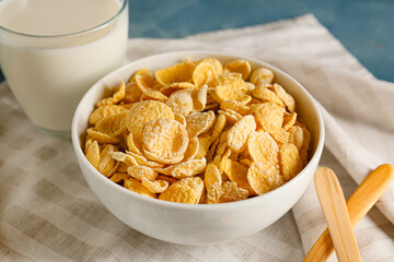 Bowl with tasty cornflakes and glass of milk on table