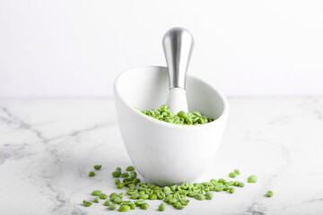 Mortar and pestle with green coffee beans on light background