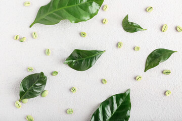 Leaves and green coffee beans on light background