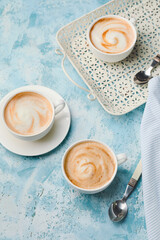 Cups of hot cappuccino on color background