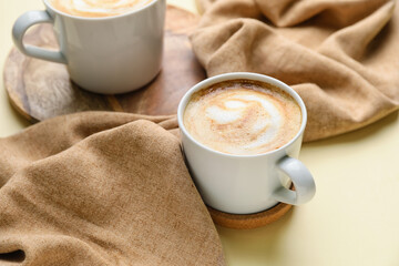 Cups of hot cappuccino on color background