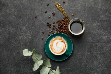 Cup of hot cappuccino and coffee pot on dark background