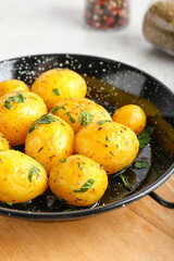 Frying pan of tasty potatoes with parsley on light background, closeup