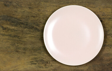 Empty pink ceramic plate on wooden rustic table, top view.