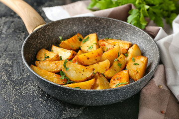 Frying pan of tasty potatoes with parsley on dark background