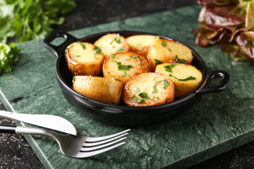 Frying pan of tasty fried potatoes with parsley on table