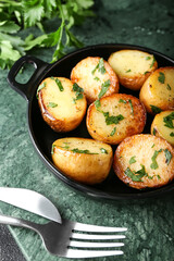 Frying pan of tasty fried potatoes with parsley on table