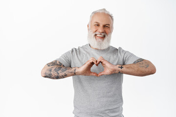 Happy mature man with tattoos laughing, showing heart I love you gesture, express sympathy, like or...