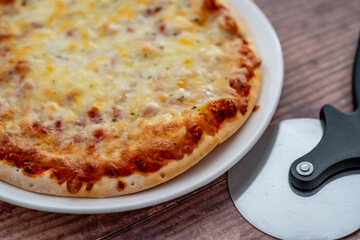 Close up and selective focus of a home cooked thin crust four cheese pizza on a white plate on a wooden table