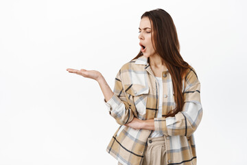 Confused woman look shocked at her hand, puzzled as if holding something strange, stare questioned...