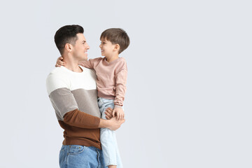 Happy father and his little son on light background