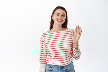 Hello nice to meet you. Smiling friendly woman wave hand and look happy, greeting you, say hi, making friends, standing over white background