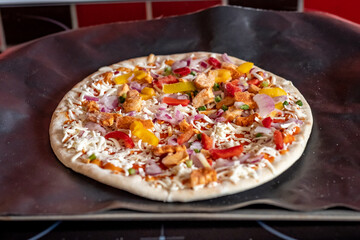 Close and selective focus of a readymade frozen stone baked thin sweet chilli chicken pizza on a...