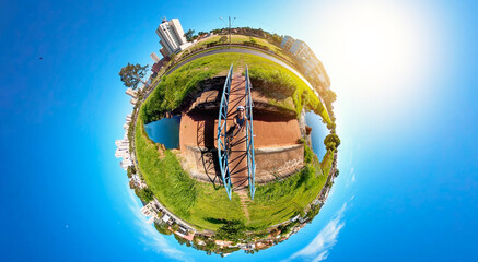 Cyclist man black with helmet and bicycle on lake bridge in a sunny blue sky day. Space for text.