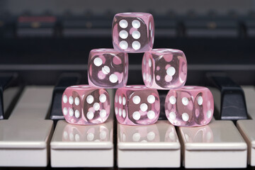 Pink dice lie on the keyboard of a synthesizer. Keys of musical instruments. Risk and gain. Hobby....