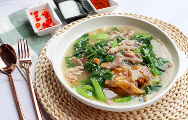 Stir fried noodles with pork and kale in gravy sauce (Thai food called Rad Na Moo) - close up view with seasoning