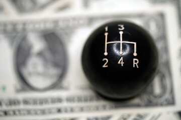The Car speed knob close-up lies a dollar banknote.  Car speed knob close-up                       ...