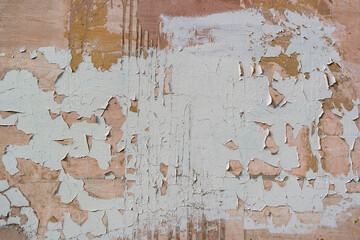 Flakes and leaks of paint over the cracked plaster on the wall