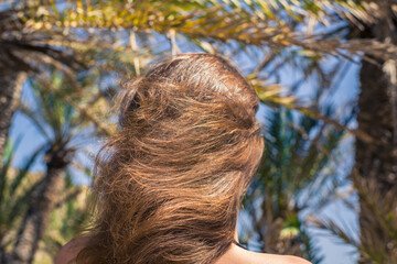 Back view on the girl with flowing hair walking in the palm forest. Seychelles islands