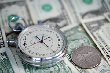 Time is money. Dollar close up. Money macro shot. The stopwatch lies on the dollars. Chronograph. Measurement. Rapidity Force Speed.