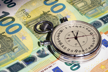 Money macro shot. The stopwatch lies in the center of the banknote layer. Clock. Time is money                                                              
