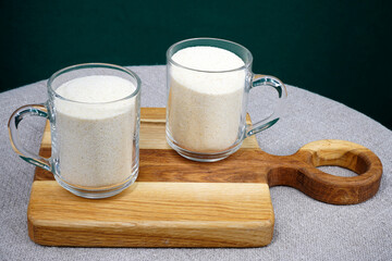 Two glass glasses with semolina are on a wooden board.                                
