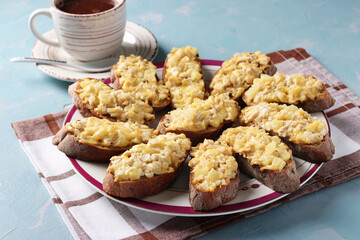Baked homemade toasts with chicken, cheese, pineapple and garlic as well cup of coffee on a light blue background.