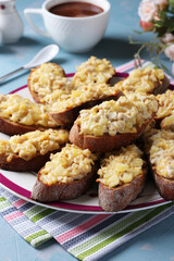 Baked homemade toasts with chicken, cheese, pineapple and garlic as well cup of coffee on a light blue background.