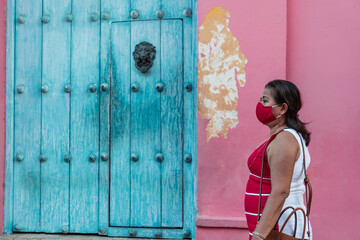 Portrait of a 50 year old woman wearing a protective mask on the street in a dress.