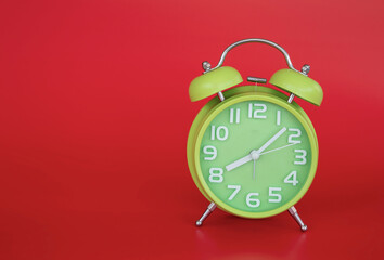 Close-up of retro green alarm clock over red background.