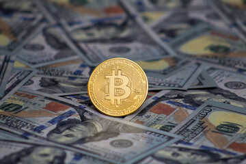 Bitcoin coin on top of 100 dollar bills