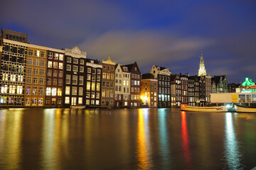 Fototapeta na wymiar Amsterdam dancing houses on Damrak illuminated lit up at night houses with dutch architecture by the canal Amsterdam Netherlands