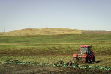 Fototapeta premium The tractor works on a green field.