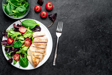 Chicken fillet with salad and spinach. Healthy food on stone background with copy space for your text
