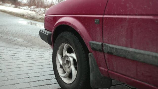A red car stops on the road. Wheel stops spinning. Cobblestone road, winter day. Emergency stop