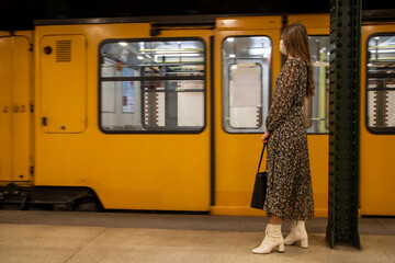 A young girl waiting for an old subway with a mask on her face during pandemic
