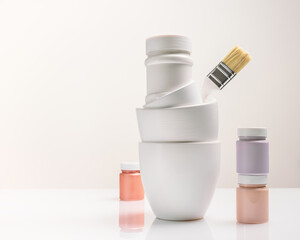 Composition with paint cans, jars and a brush on a light background with copy space. Mockup for paints, lacquers. Artist's workplace, preparation for decorative, creative and artistic works