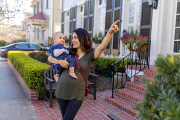 Beautiful happy mother holding her cute baby in peaceful neighborhood