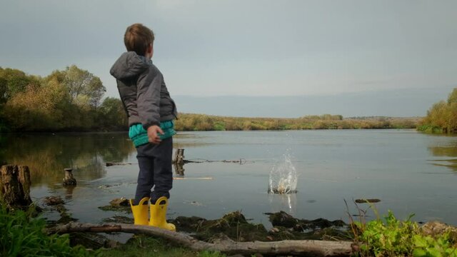 Disabled boy throws a stone into the water. Slow motion